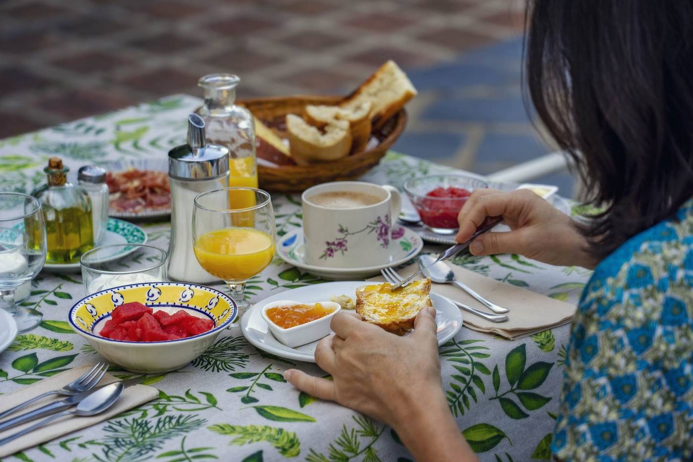 Tostada con aceite de oliva y desayuno servido en mesa con mantel de hojas verdes